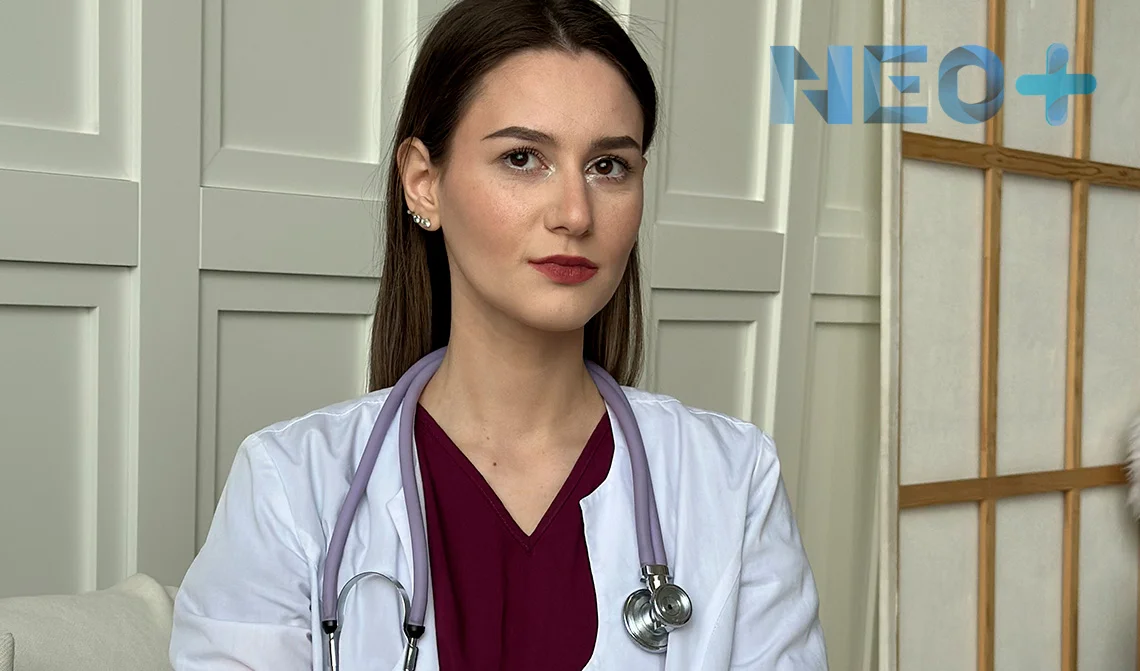 женщина врач в белом халате смотрит в камеру